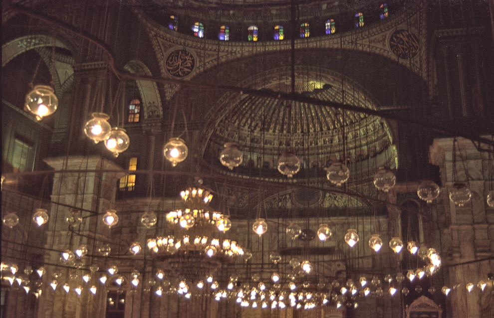 Arcate decorate e numerose lamapade accese disposte in cerchio nella Moschea di Muhammad Ali a Il Cairo.