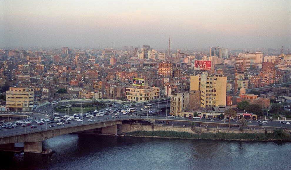 Lunghi ponti sul nilo pieni di automobili e la città del Cairo sullo sfondo.