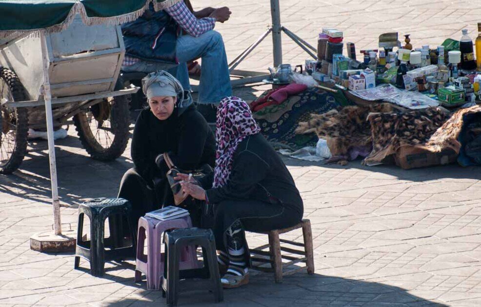 Piazza Jeema El Fna Due donne che fanno tatuaggi con l'Henné chiaccherano in attesa di clienti