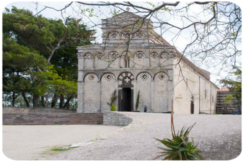 Facciata principale di una chiesa in mezzo al verde in Sardegna.