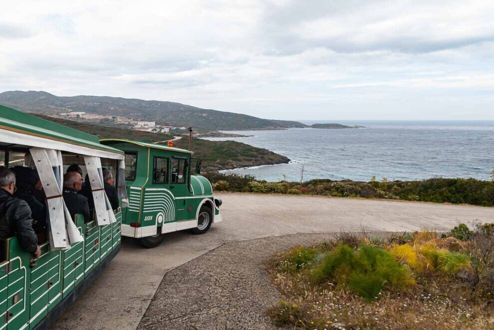 Parte delle carrozze di un trenino turistico in viaggio lungo le stradine dell'Isola dell'Asinara.