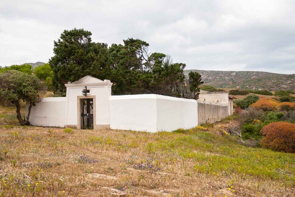 Un muro bianco con una croce sopra l'ingresso del cimitero di Cala d'Oliva che raccoglie i resti degli antenati di Stintino. 