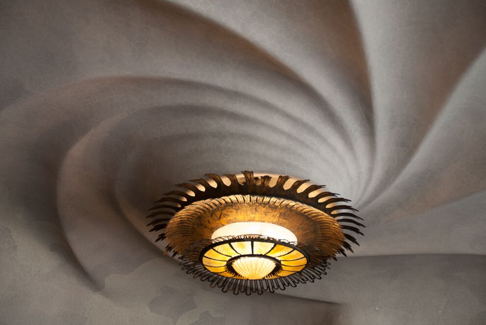 Casa Batllo soffitto Al primo piano, dietro le enormi finestre della facciata, si trova lo spazio abitativo principale della famiglia Balltó , che si affaccia direttamente sul Passeig de Gràcia. Dovremmo anche notare il soffitto rialzato a forma di spirale gigante, che ricorda l'atmosfera marina. Il grande lampadario dello spazio simboleggia il sole.