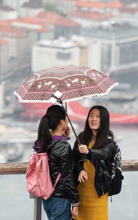 Due ragazze asiatiche sul monte Floyen Due ragazze asiatiche si riparano sotto un ombrello si fanno un selfie sul monte Floyen