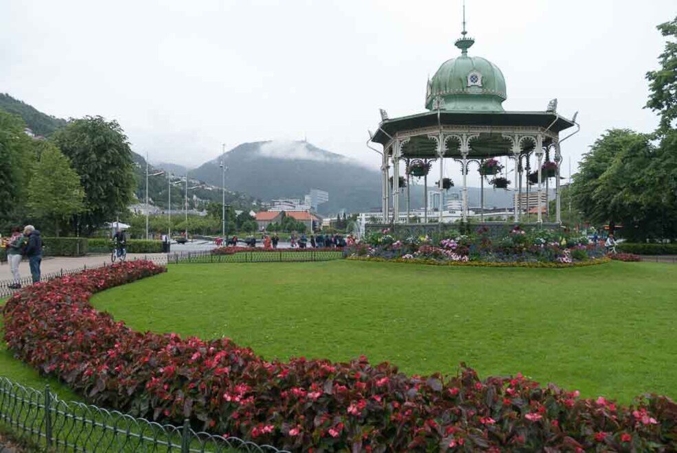 Byparken a Bergen, circondato da musei d’arte. Un parco con giardini verdi e fiori rossi e un monumento che termina con una cupola in alto.