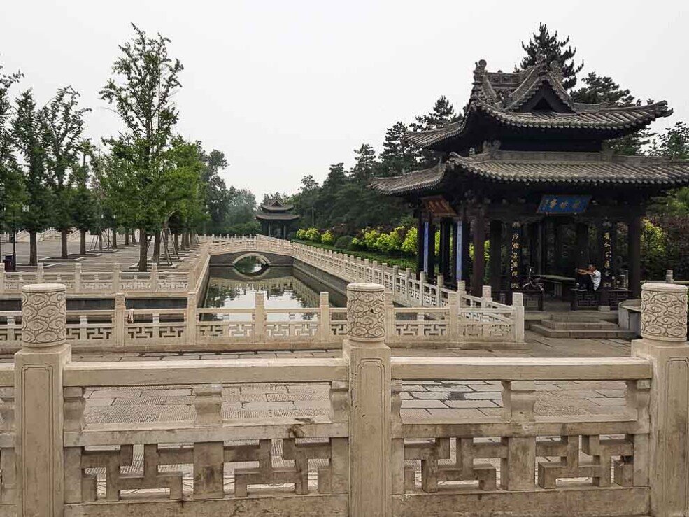 Un camminamento in pietra che conduce a una pagoda, immersa nel contesto del Tempio Jinci, circondata da natura.