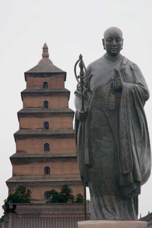 Un buddha in piedi in primo piano e sullo sfondo la Pagoda della Grande Oca Selvatica a Xi'an.