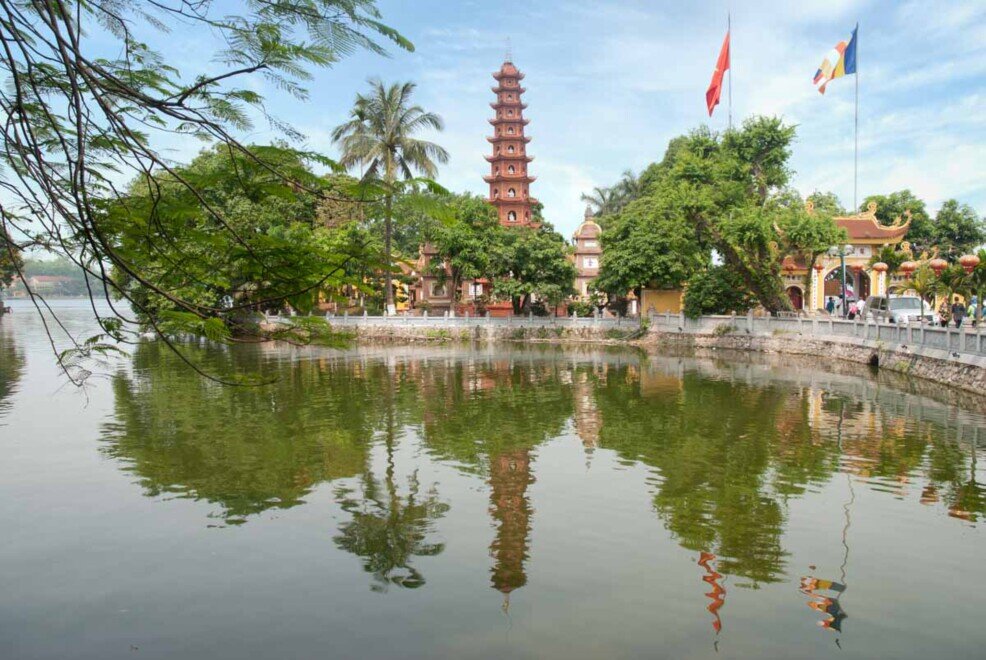 Un grande lago su cui si riflette una pagoda a più piani rossa.