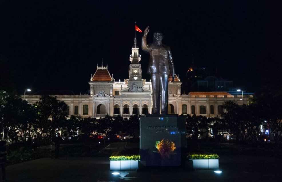 Una grande statua in primo piano e sullo sfondo il municipio di Ho Chi Minh.