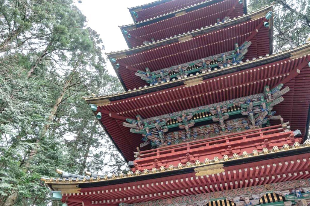 La pagoda a cinque piani di Toshogu Pagoda a cinque piani di Toshogu nel bosco, caratterizzata da tetti multicolori che si integrano con la natura circostante.