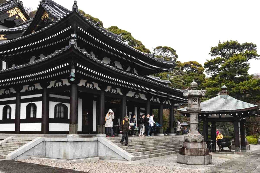 Sala Kannon-do Grande edificio con un gruppo di persone all'esterno, che interagiscono e osservano l'architettura.
