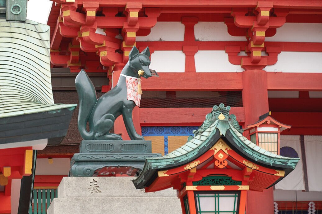 La volpe sacra messaggera del Dio Inari al tempio Fushimi Inari-Taisha La statua di una volpe su un piedistallo con una chiave in bocca.