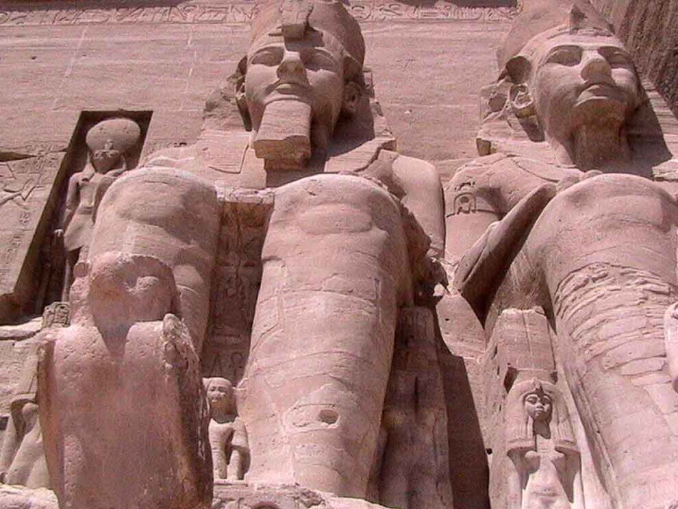 Due enormi statue con una più piccola di un falco al tempio di Assuan.