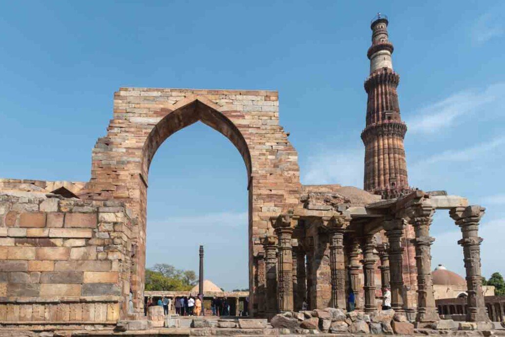 Arco e torre del Qutb Minar Un arco e una alta torre con colonne, testimonianze di un antico minareto mai terminato di costruire.