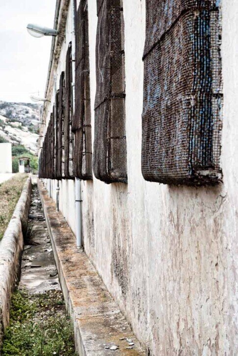 Una parete del carcere dell'Asinara con una lunga fila di finestre chiuse da sbarre