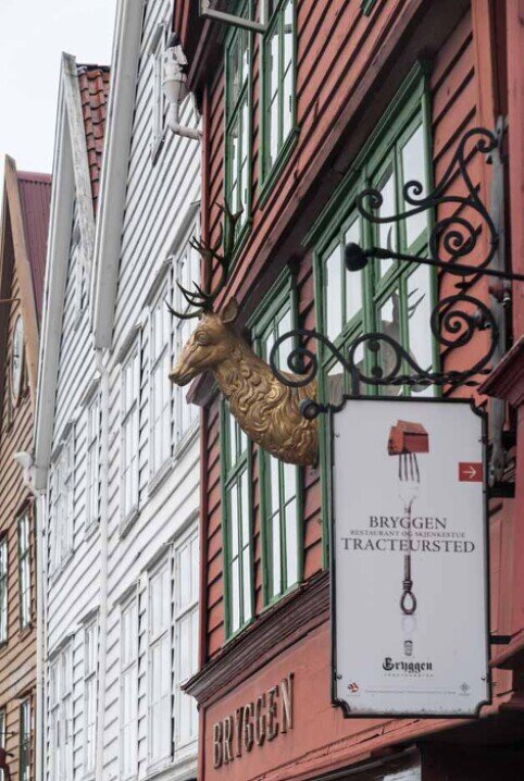 Facciate delle case di legno e insegne dei negozi nel quartiere di Bryggen del lungomare storico della città di Bergen.