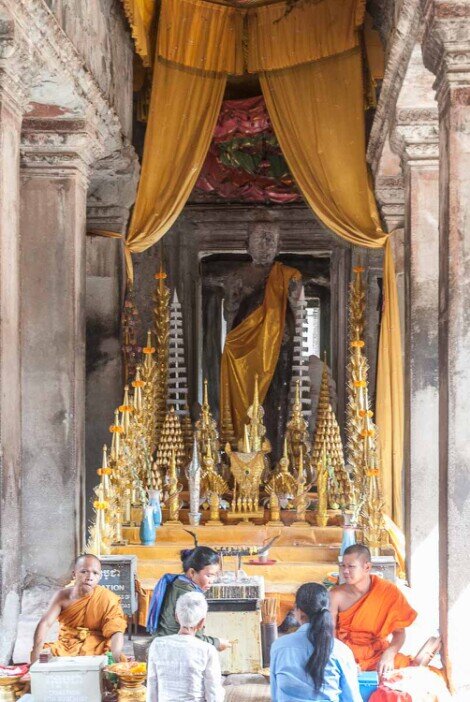 Un piccolo tempio buddista con persone che pregano in un livello del tempio di Angkor Wat.