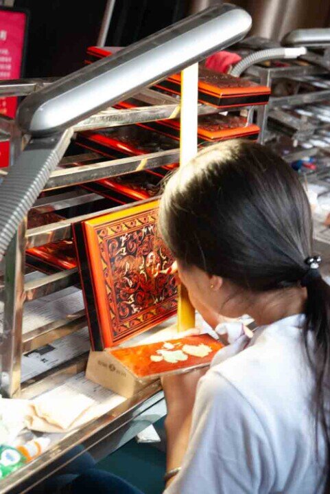 Ragazza dipinge con la lacca una ceramica. Le ceramiche laccate di Pingyao rivivono dal passato.