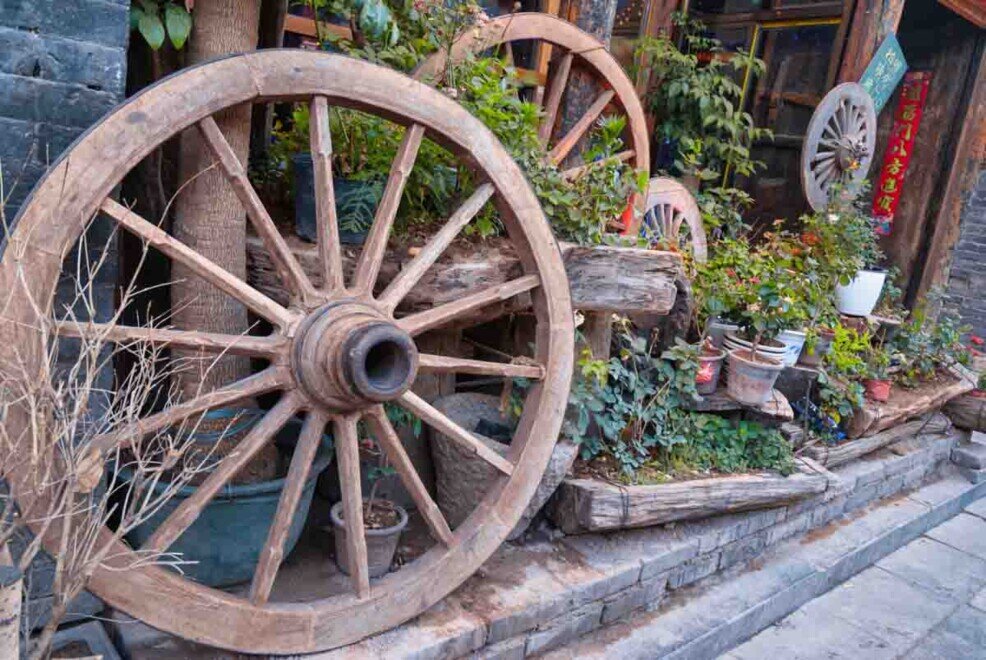 Grandi ruote in legno appoggiate fuori dai locali (ristoranti, negozi, hotel) nell'antica città di Pingyao a scopo decorativo.