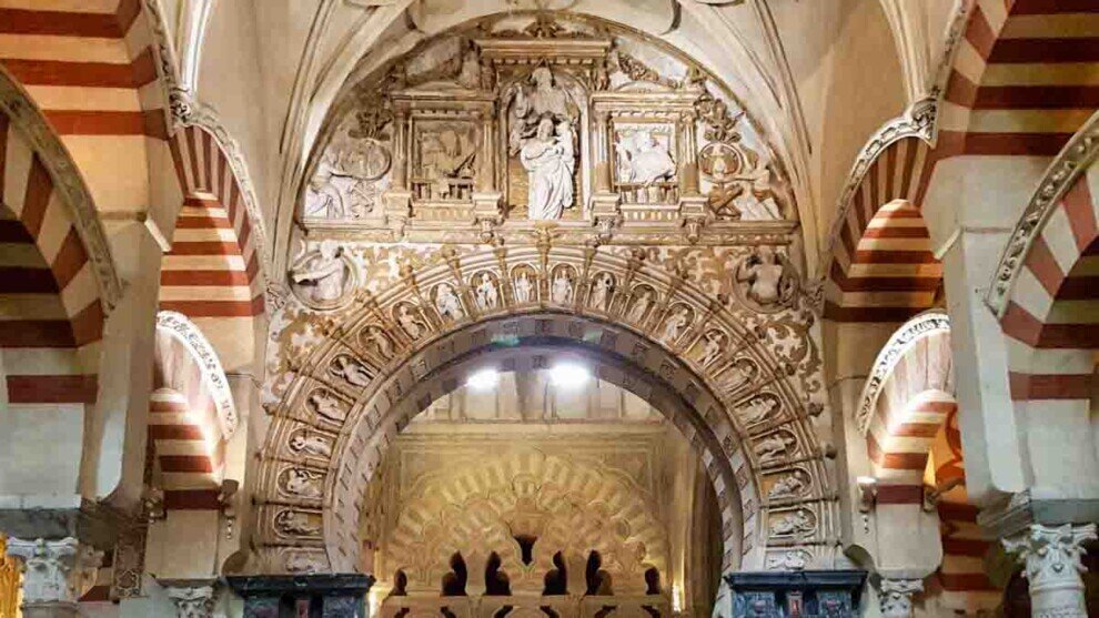 Accesso alla Cappella di Villaviciosa nella Mezquita di Córdoba con arco decorato, stucchi rinascimentali e colonne bicolori rosse e bianche.
