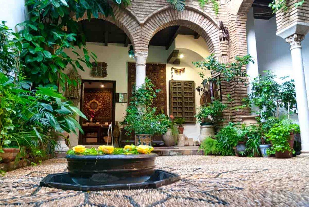 Patio della Casa Andalusi a Cordova con archi in mattoni, fontana centrale e piante ornamentali