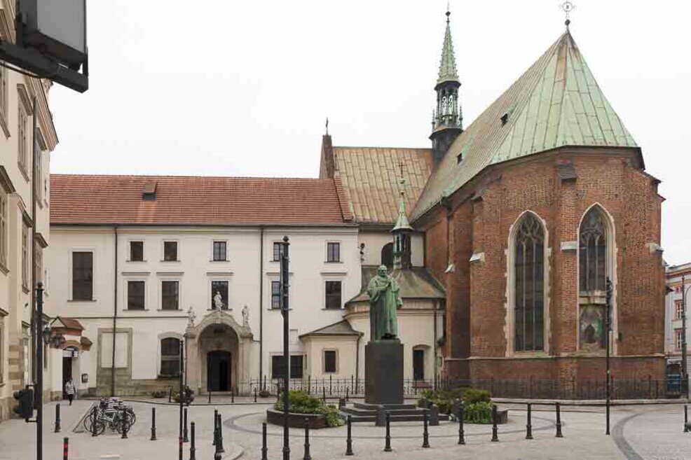 Un cortile con una statua e alle sue spalle una basilica.