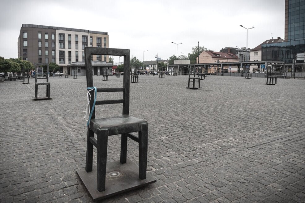 Settantsa sedie vuote sparse in una grande piazza.