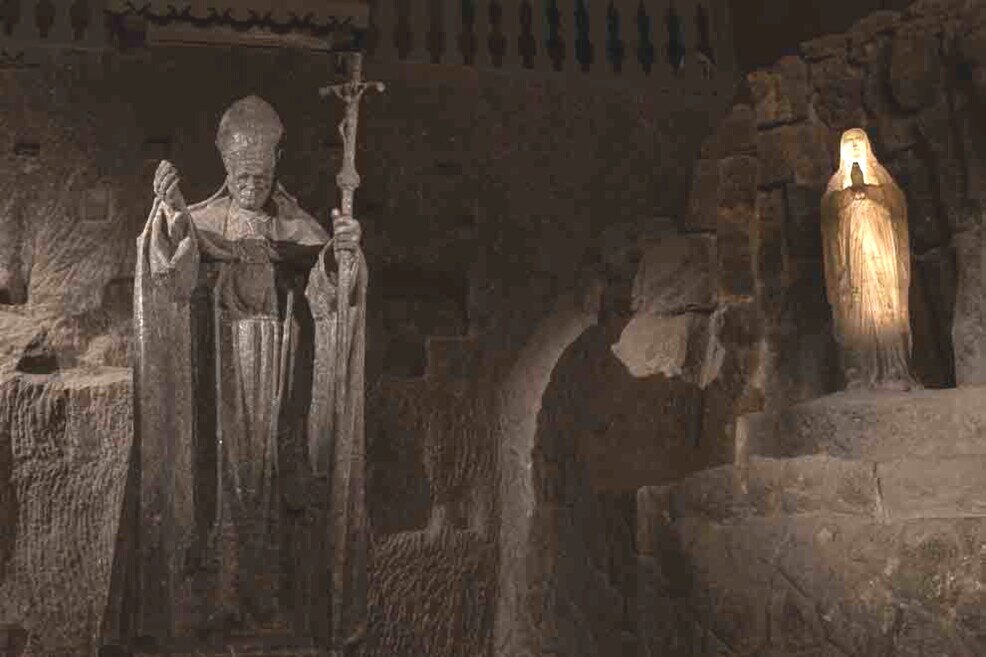 Una statua di papa Giovanni Paolo II a grandezza naturale con una più piccola della madonna con le mani giunte, all'interno della grotta del sale di Cracovia.