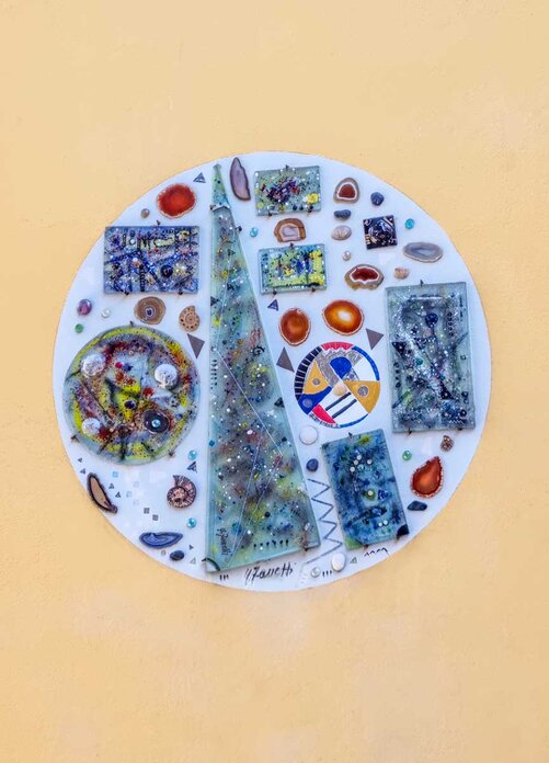 Il murale su sfondo ocra è composto da un cerchio bianco con all'interno varie figure geometriche e organiche.
