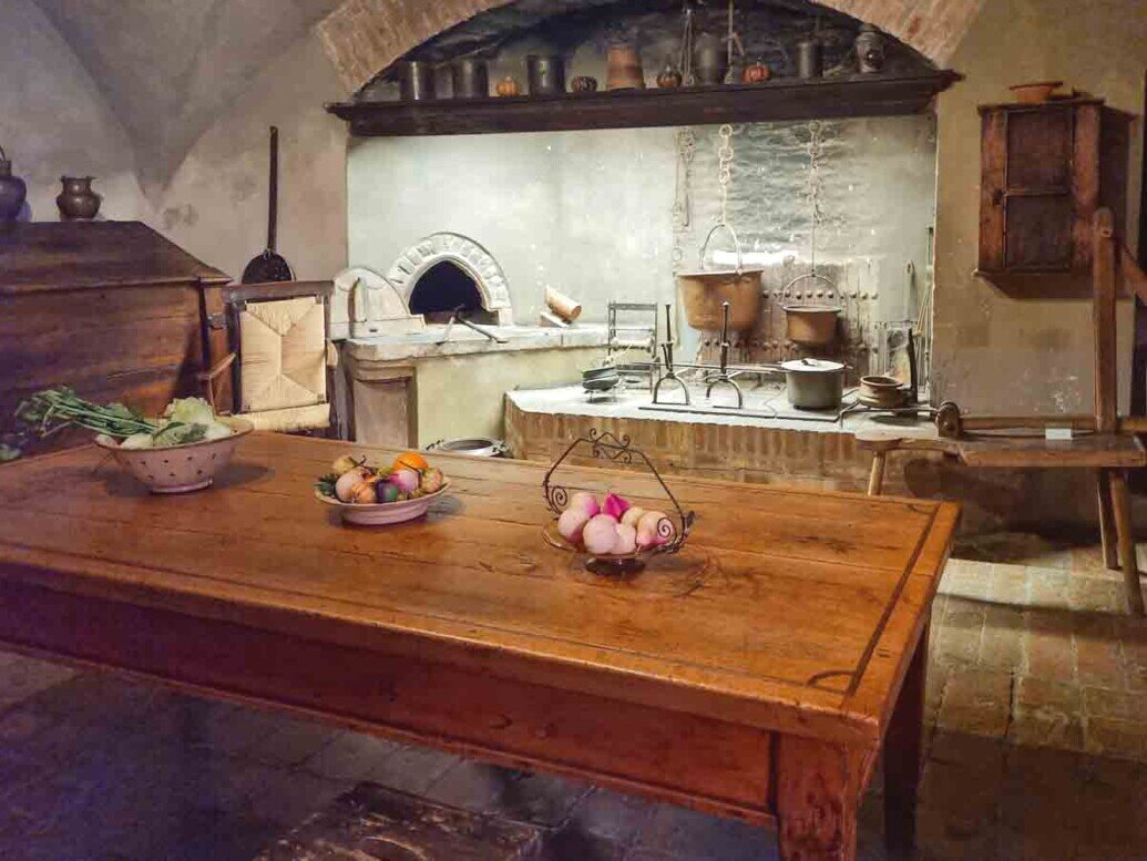 Un tavolo in legno un forno a legna ripiani e materiali da cucina nella rocca di Dozza.