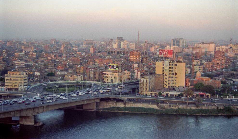 Lunghi ponti sul nilo pieni di automobili e la città del Cairo sullo sfondo.