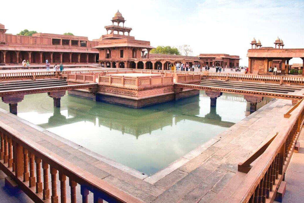 Vista della piazza dell'antico edificio di Fatehpur Sikri, con grande vasca su cui si riflette l'architettura circostante.