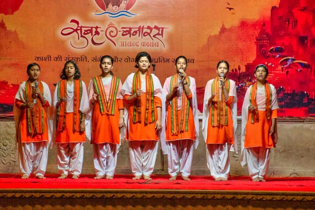 Coro di ragazze all'Aarti Cerimonia Aarti a Varanasi con un gruppo di donne in abiti arancioni che cantano.