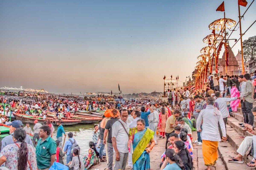 Ghat affollato a Varanasi Folla sui gradini di un ghat a Varanasi, con barche ancorate lungo il fiume.