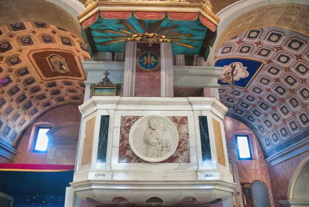 Un pulpito marmoreo con ai fianchi i soffitti ad arco decorati di una navata.