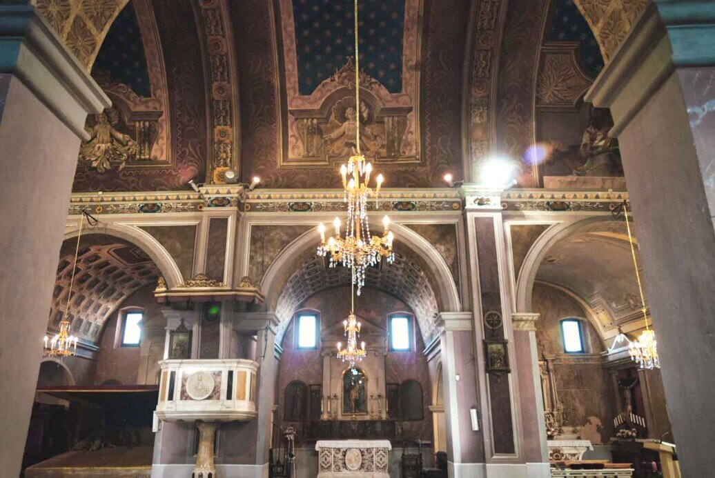 Una delle navate laterali della chiesa con archi decorazioni e un pulpito.