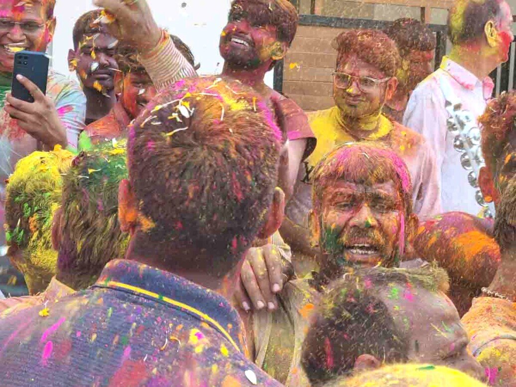 Festeggiamenti all'holi festival Gruppi di uomini che ballano completamente ricoperti di polveri colorate sul viso, sui capelli e sui vestiti.