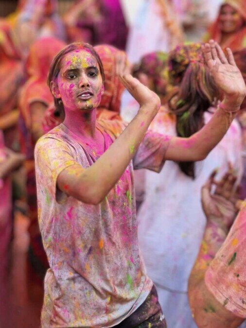 Ragazza che balla Una ragazza interamente ricoperta di colori balla con le braccia sollevate.