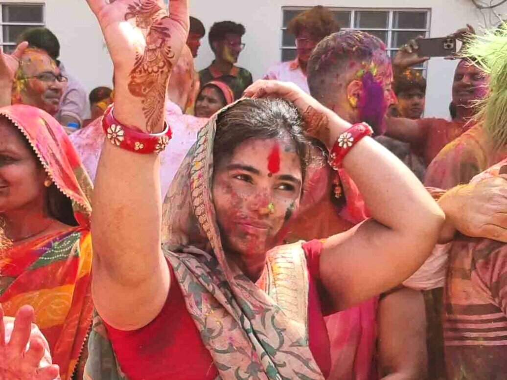 Donna in sari colorato con le mani alzate mostra tatuaggi all'henné.