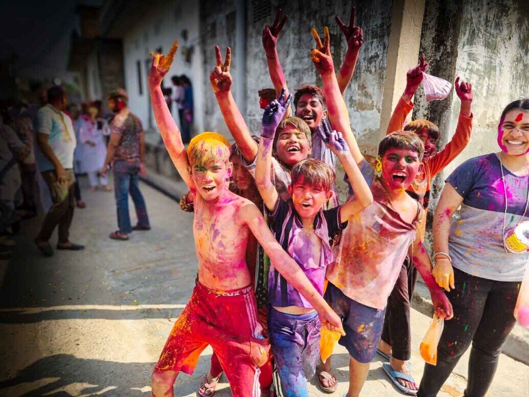 Un gruppo di ragazzini si mettono in posa felici di essere fotografati ricoperti di polveri colorate all'holi festival.