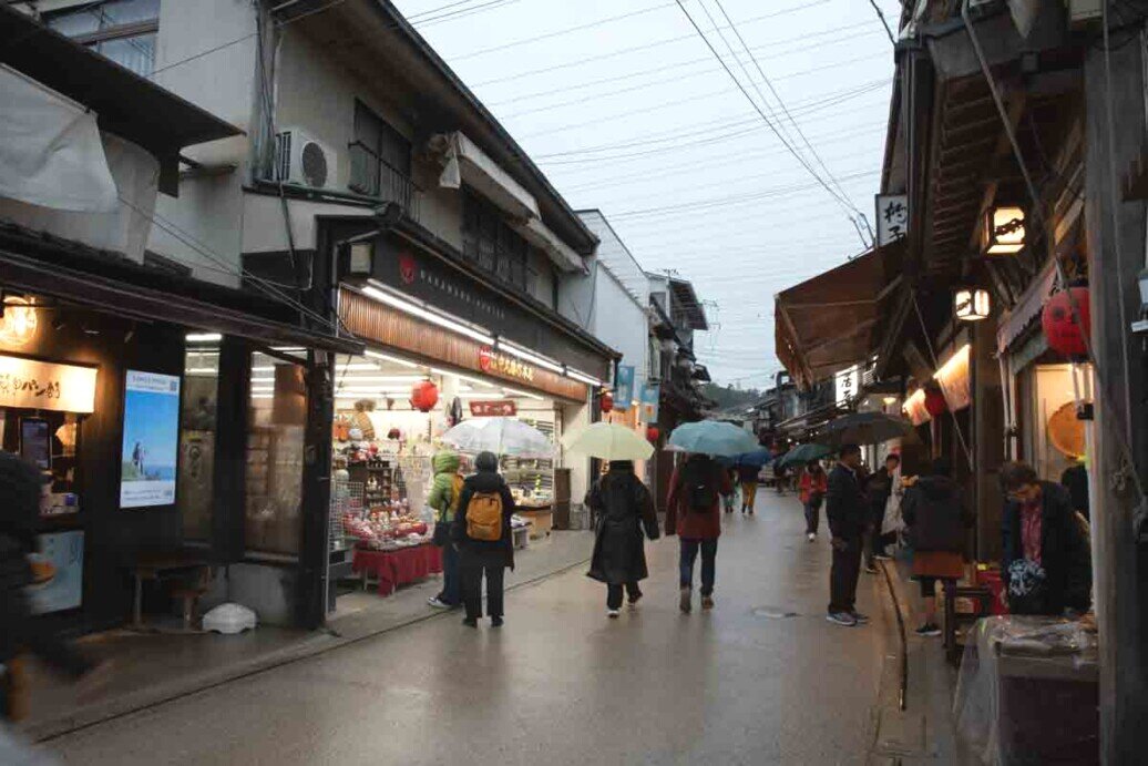 Una strada di Miyajima con due file di negozi che vendono souvenir e specialità del posto.