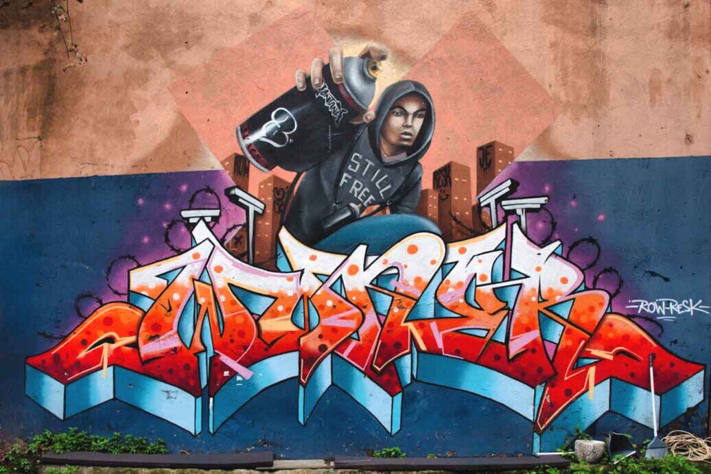 Murale che raffigura un ragazzo con in mano una bomboletta spray pronto per disegnare su un muro.