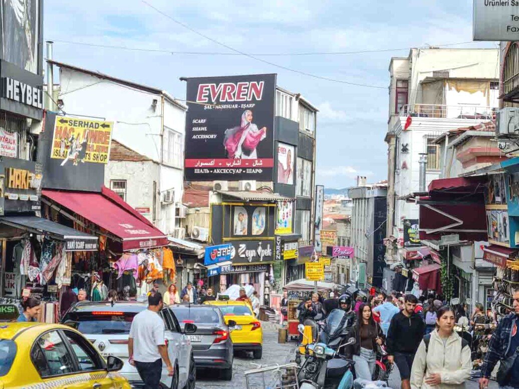 Strada commerciale di Istanbul con tanta gente e traffico di auto.
