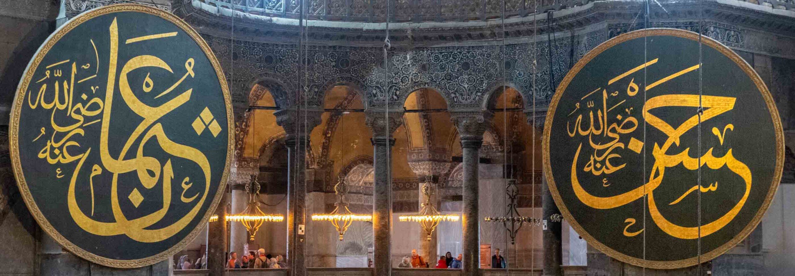 Due grandi cerchi in legno con sfondo nero e scritte gialle con la grafia ottomana appesi sulla parete interna della Basilica di Santa Sofia.