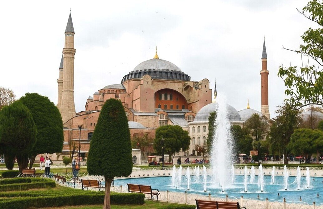 Una fontana zampillante davanti alla Basilica di Santa Sofia convertita in moschea con minareti ai suoi lati.