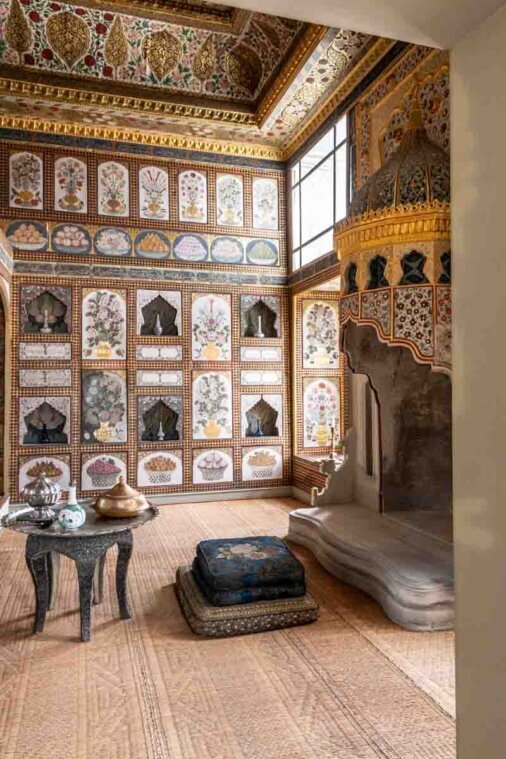 Una camera variopinta con pavimento elaborato, un camino, e una parete in legno con dipinti floreali e di frutta.