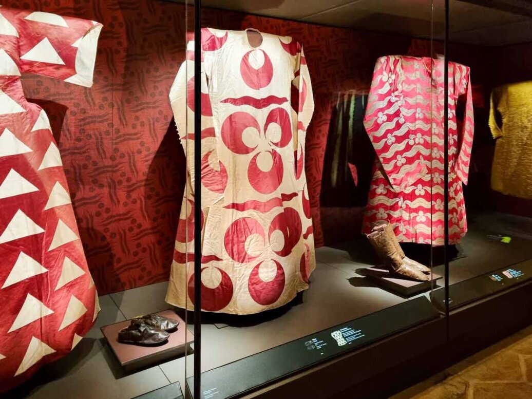 Dentro una vetrina sono esposti tre sontuosi abiti dei sultani con disegni o sfondi rossi, insieme  a pantofole e stivaletti. 