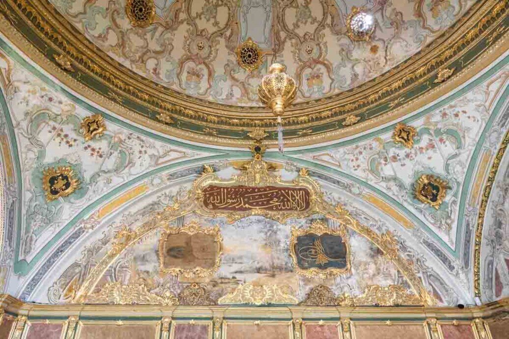 Una cupola con intricati motivi floreali ottomani con una targa di legno con una scritta che si traduce in "Dio vi benedica". Appesa al centro della cupola c'è una palla d'oro che indica la terra.