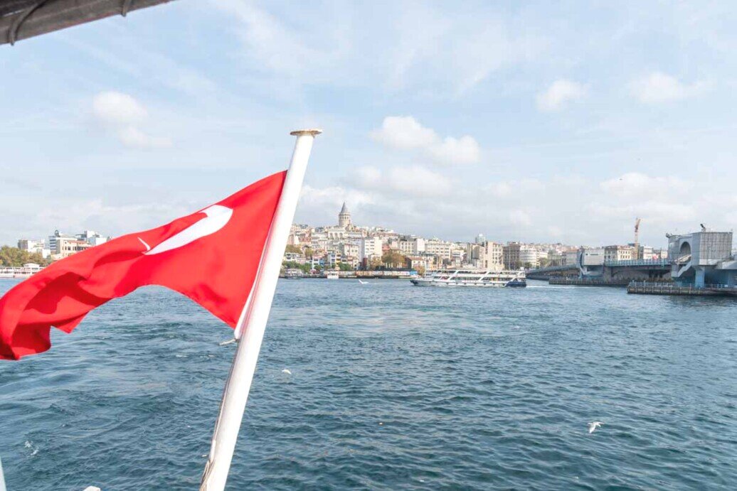 Una bandiera della Turchia sventola sulla poppa di una imbarcazione con sullo sfondo il Bosforo.