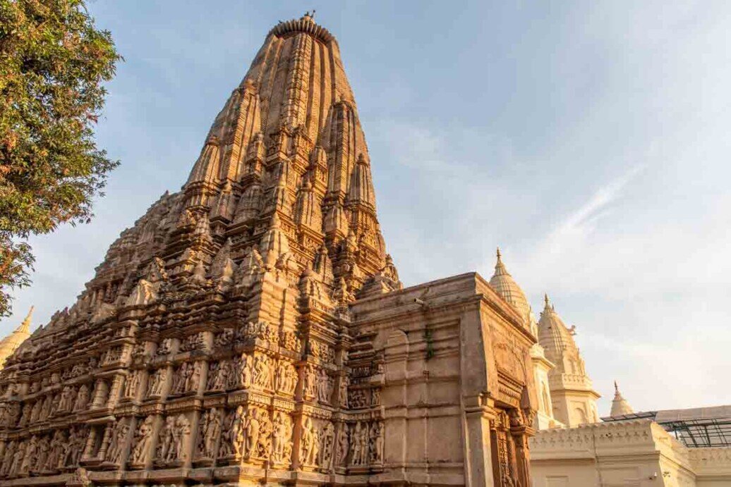 Tempio di Parshwanath a Khajuraho, India: veduta ravvicinata della torre riccamente scolpita con bassorilievi raffiguranti divinità e scene mitologiche.
